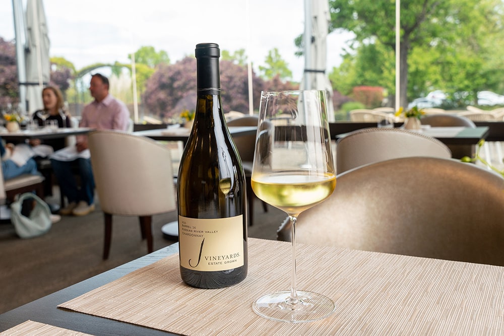 J Vineyard white wine bottle on table with glass