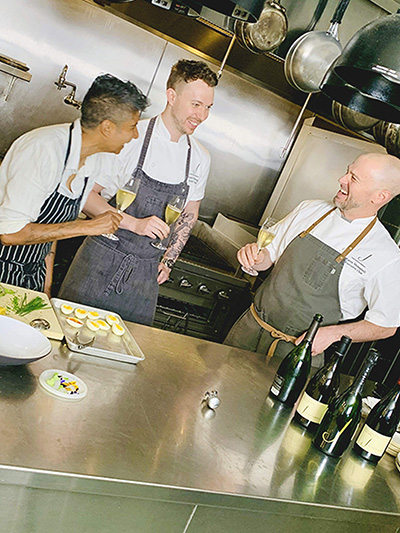  Chefs toasting with glasses of wine in the kitchen