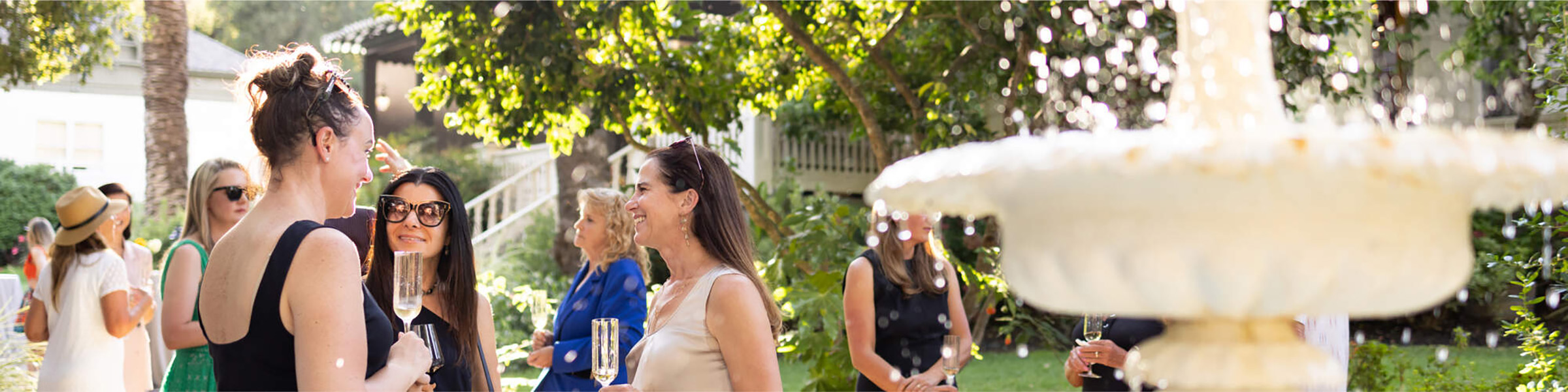 People gathered at an outside event enjoying wine.