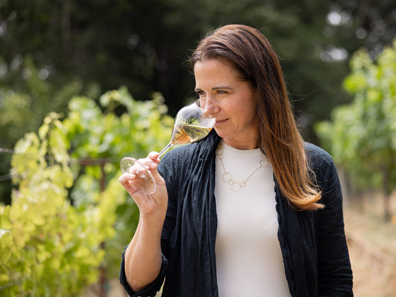 Winemaker Nicole Hitchcock drinking wine in the vineyard.